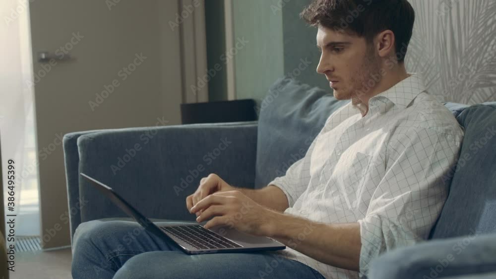 Wicked guy working computer indoors. Angry man messaging laptop in hotel room. Wicked guy working computer indoors. Angry man messaging laptop in hotel room.
