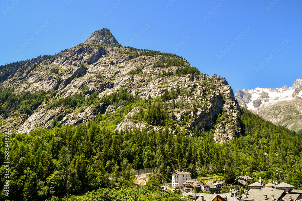 Rooftop view of the old mountain village at the foot of Mount Chetif with the Mont Blanc mountain range in the background in a sunny summer day, Courmayeur, Aosta Valley, Italy