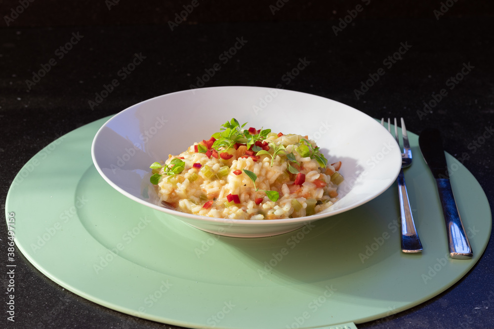 Tomato risotto with buffalo mozzarella and dwarf basil leaves on a white plate Tomato risotto with buffalo mozzarella and dwarf basil leaves on a white plate