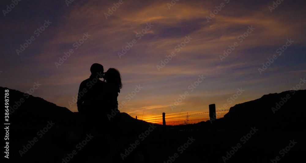 silhouette of a couple with sunsets behind
