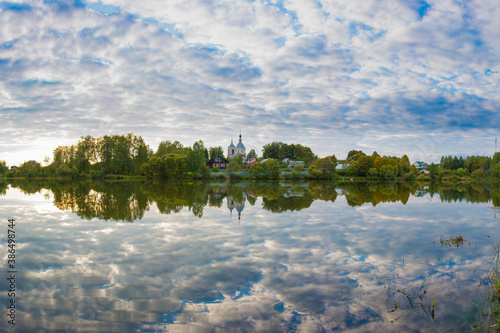 Lake with reflection of clouds and a church on the shore. Russian landscape. photo