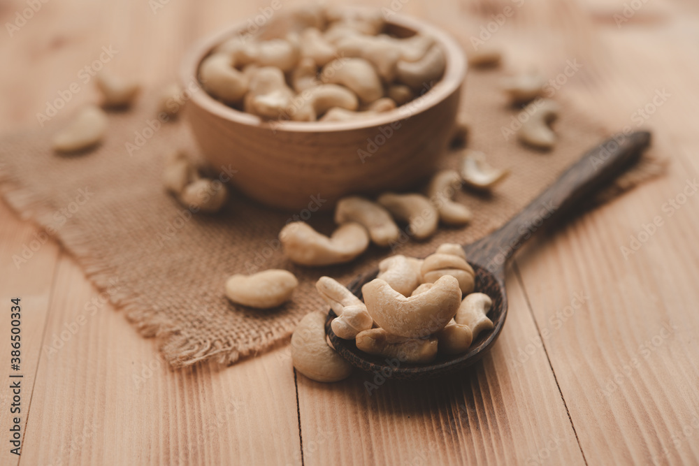 raw cashew nuts in wooden bowl on rustic table, healthy vegetarian snack raw cashew nuts in wooden bowl on rustic table, healthy vegetarian snack