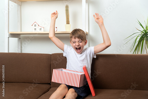Boy teenager rejoices and has fun having received gift. Happy child with gift