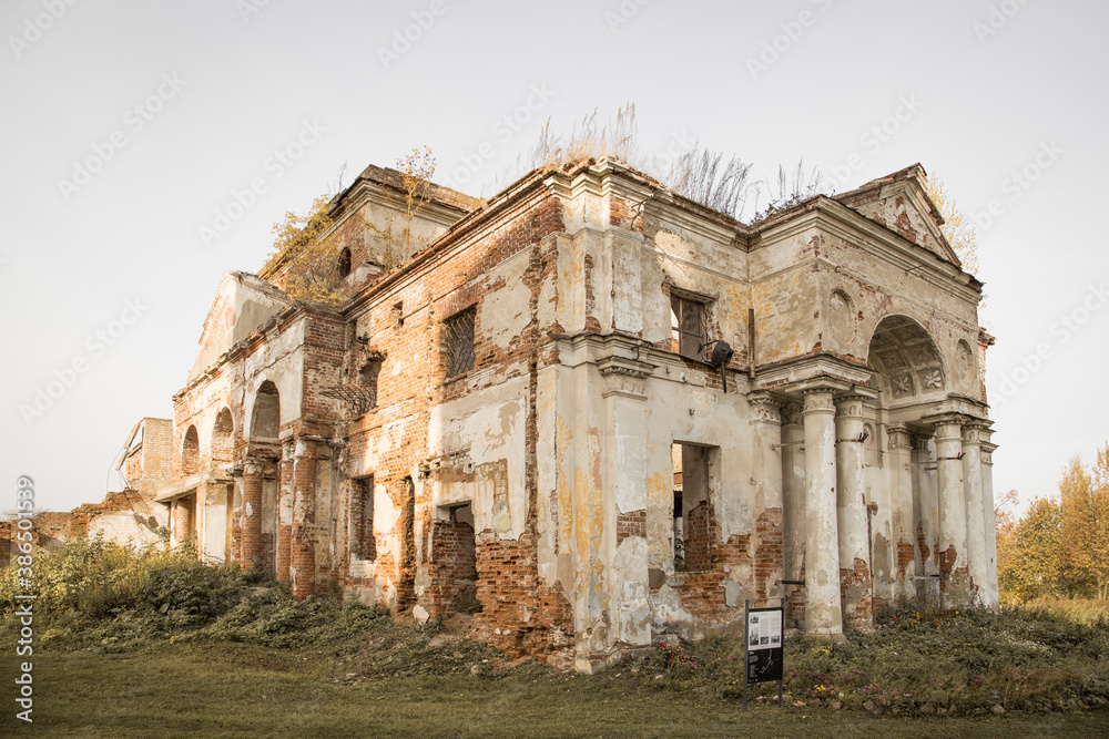 Ruins of a Russian Orthodox church with brick walls and crumbling plaster. Autumn colours, clear sky, no people.