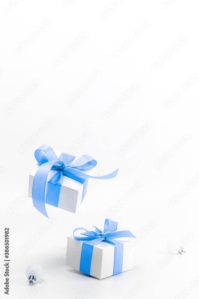 Fototapeta premium Christmas sale. White gift box with blue ribbon, New Year balls in xmas composition on white background for greeting card. Christmas, winter, new year concept.