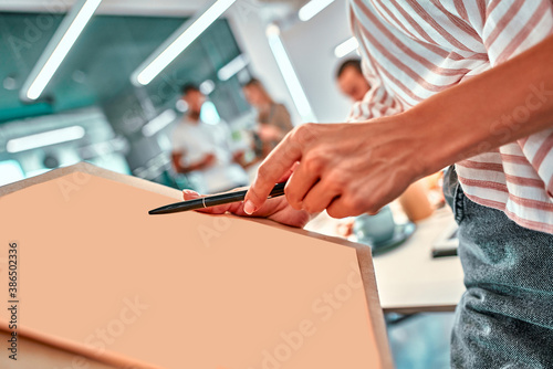 A hand holding a pen and a paper sheet at a business meeting