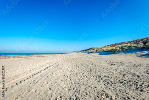 Empty sandy beach on the Dutch North Sea coast near the village of Domburg on the Zeeland island of Walcheren. It is a beautiful winter day with a bright blue sky.