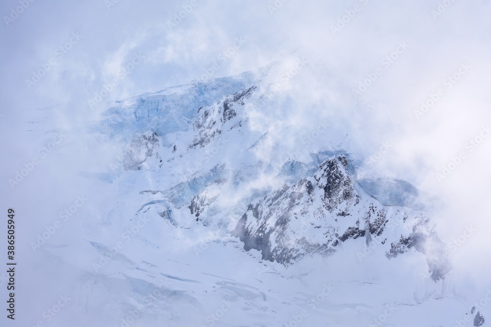 a mountain of snow covered by clouds and fog a mountain of snow covered by clouds and fog