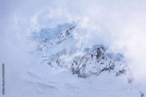 a mountain of snow covered by clouds and fog
