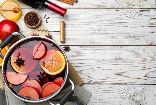 Delicious mulled wine and ingredients on white wooden table, flat lay. Space for text