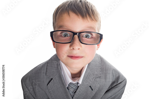 Portrait of a funny child boy wearing glasses against a white background. Smart child in suit and glasses looking at camera. Back to school and education concept