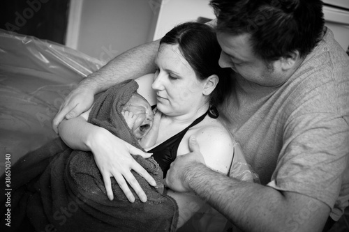 Wife and Husband Holding Newborn Baby in Birthing Pool After Home Birth