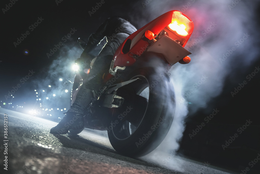Motorbiker is burning a tire rubber on night road. - obrazy, fototapety, plakaty 