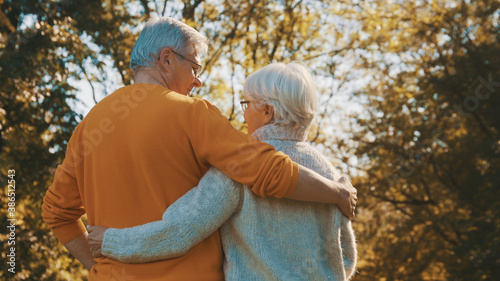 Happy old couple hugging in park. Senior man flirting with elderly woman. Romance at old age on autumn day. High quality photo