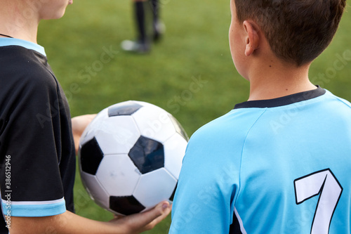 close-up photo of ball in hands of football player, cropped child boy in uniform going to play © Roman