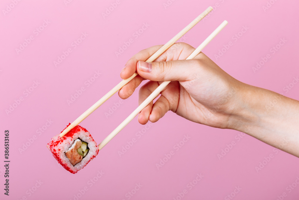 Tasty sushi roll California with wooden chopsticks on pink background close up. Place for caption and text