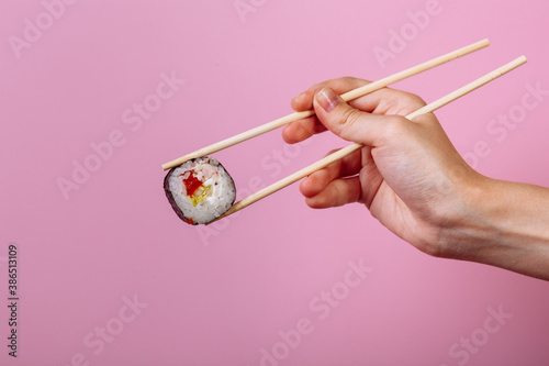 Tasty sushi roll maki with wooden chopsticks on pink background close up. Place for caption and text