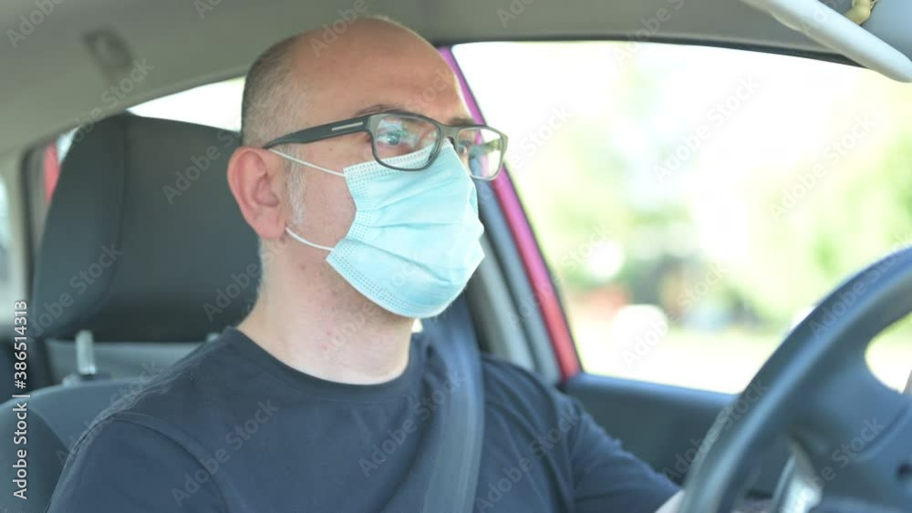 Escaping home life, driving to new destinations. In the covid era, a Caucasian man with a mask to defend himself from the coronavirus drives his car to new destinations: he is focused on driving. Escaping home life, driving to new destinations. In the covid era, a Caucasian man with a mask to defend himself from the coronavirus drives his car to new destinations: he is focused on driving.