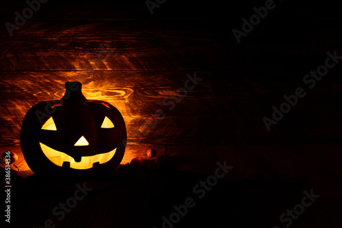 Halloween pumpkin lanterns on a wooden background. The yellow light of the scary pumpkins illuminates its surroundings.