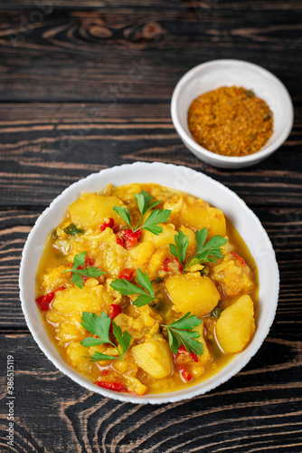 Aloo Gobi side dish. Traditional spicy vegetarian indian curry dish with potatoes, cauliflower, spinach with spices