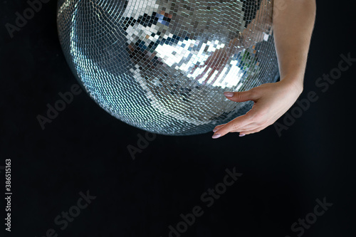 woman hand on a silver disco ball. Dance club, nightlife, parties. Close-up, black background