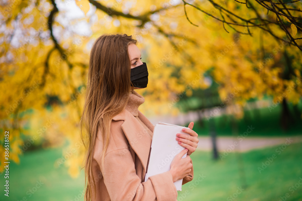 Naklejka premium Young woman protecting from corona virus when walking in park. Autumn background.