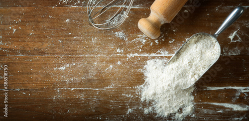 Принти на полотні Scoop with flour on floured wooden pastry board with rolling pin and whisk, top view, space for text