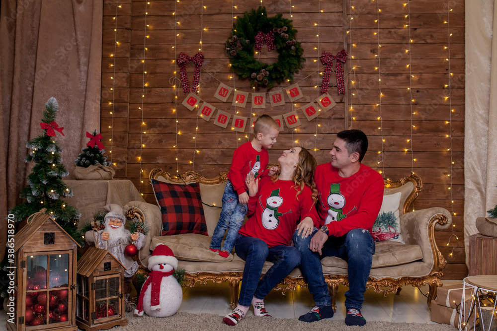Christmas Family. Happiness. Portrait of dad, mom and sonsitting on a couch at home near the Christmas tree, all are smiling. The concept of family winter holiday. Christmas Family. Happiness. Portrait of dad, mom and sonsitting on a couch at home near the Christmas tree, all are smiling. The concept of family winter holiday.
