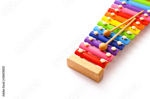 Rainbow colored toy xylophone with two sticks on white background. Copy space