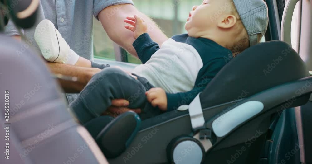 Young bearded father cares of baby boy in cap, who sits in the baby car seat inside of family car, and fastens the safety belts. Then touches baby's head and cheek. Slow motion Young bearded father cares of baby boy in cap, who sits in the baby car seat inside of family car, and fastens the safety belts. Then touches baby's head and cheek. Slow motion
