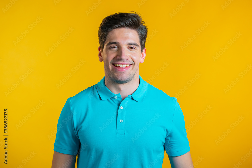 Portrait of smiling cheerful handsome man in blue t-shirt looking to camera. Guy in studio on bright yellow background. Portrait of smiling cheerful handsome man in blue t-shirt looking to camera. Guy in studio on bright yellow background.