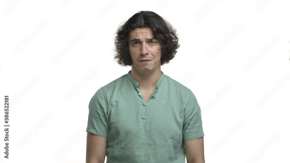 Handsome hispanic man with long dark hair, looking miserable and gloomy, shaking head and grimacing upset, standing uneasy over white background Handsome hispanic man with long dark hair, looking miserable and gloomy, shaking head and grimacing upset, standing uneasy over white background