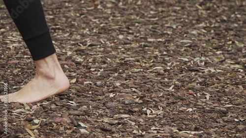 Static shot of a woman walking barefoot on tree bark floor at the forest