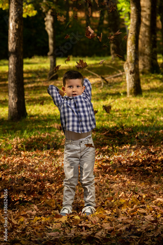 Boy throws leaves in the air.