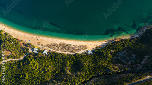 Aerial view of blue Atlantic ocean, green forest mountains and sandy Praia do Portinho da Arrabida beach. Serra da Arrabida, Portugal.