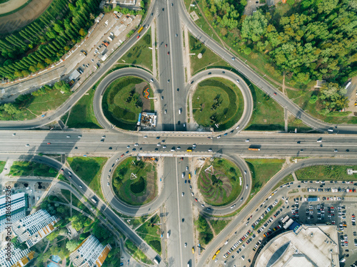 Aerial view of highway and overpass with green roadsides in city on a sunny day.