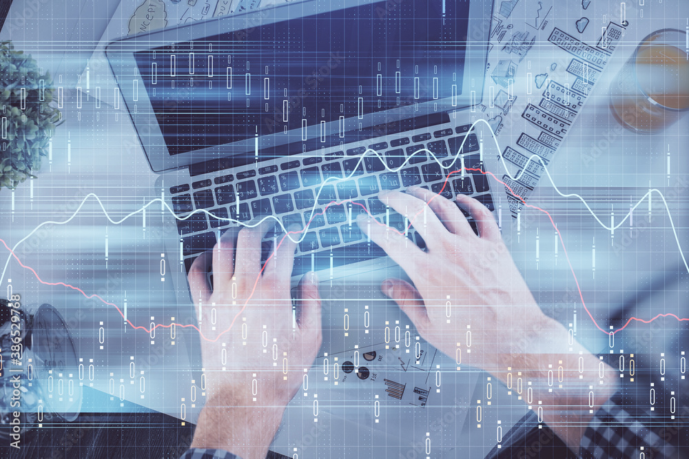 Double exposure of man's hands typing over laptop keyboard and forex chart hologram drawing. Top view. Financial markets concept. Double exposure of man's hands typing over laptop keyboard and forex chart hologram drawing. Top view. Financial markets concept.