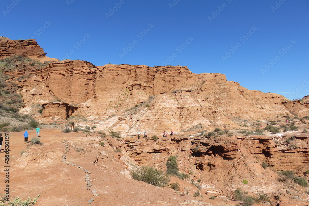 Vista de acantilados prehistóricos, con personas caminando y los acantilados de color rojo .