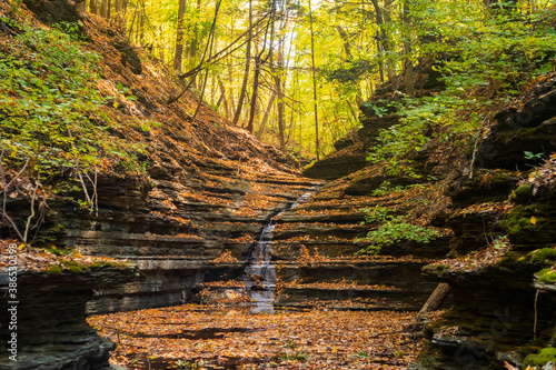 The waterfalls at Thayer Preserve Lick Brook flow at a trickle during an autumn afternoon. Fall foliage can be seen from within the gorge.  photo