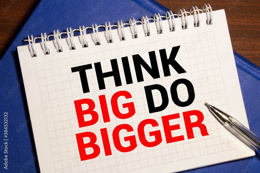 Think Big, Do Bigger Motivation quote notepad writing on dark background with pen. Think Big, Do Bigger Motivation quote notepad writing on dark background with pen.