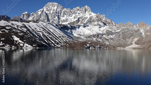 Landscape with snow covered Himalayan mountains that are reflected in a lake in Nepal.