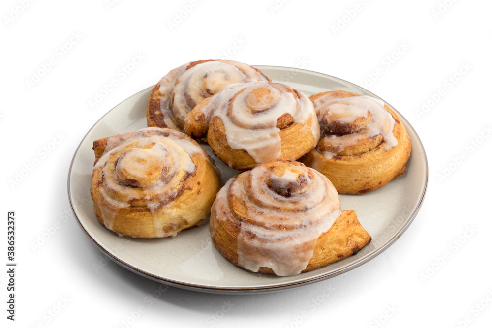 a plate full of five fresh cinnamon buns with cream cheese icing isolated on white
