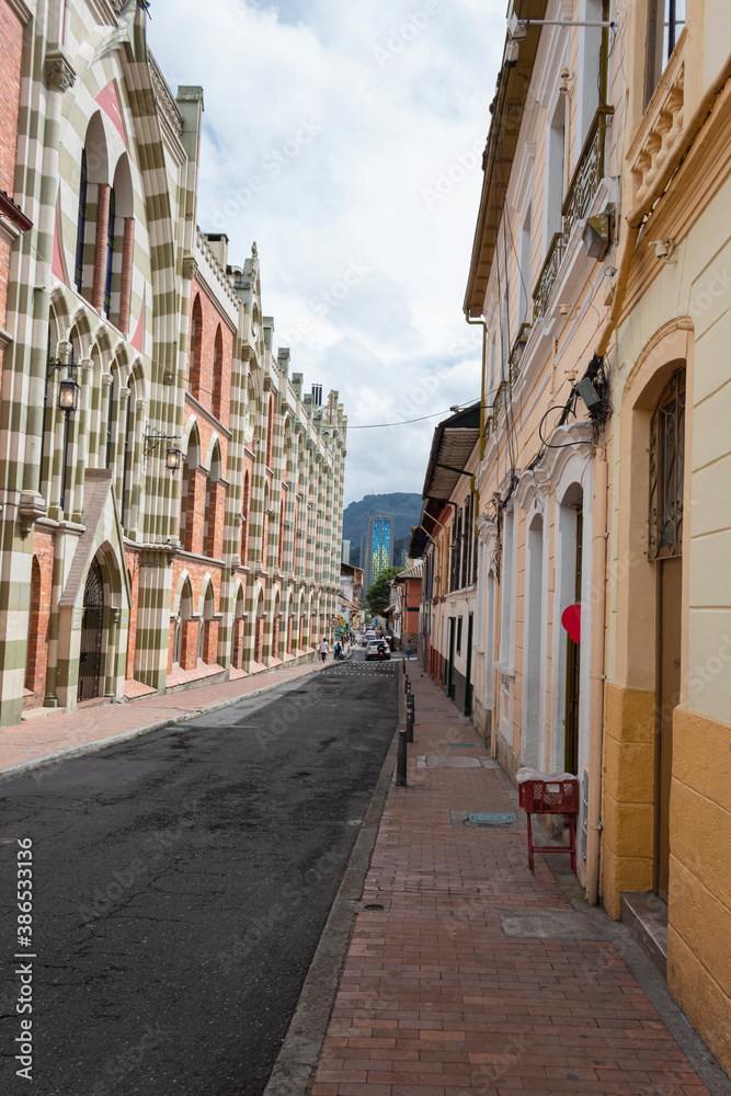BOGOTA, COLOMBIA  La Candelaria, a famous colonial neighborhood street with colored houses and modern skyscraper at background with cloudy sky