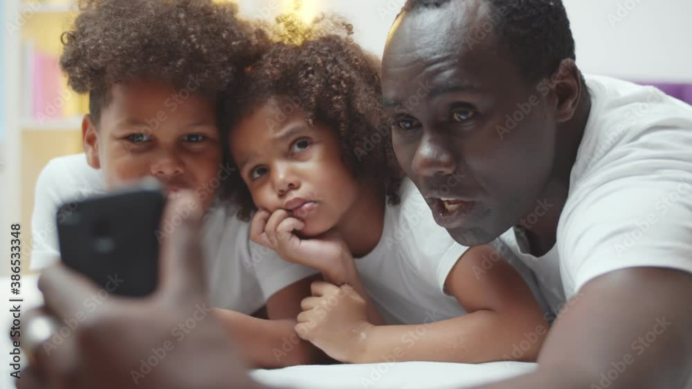Happy african american father with little son and daughter taking selfie on smartphone at home Happy african american father with little son and daughter taking selfie on smartphone at home