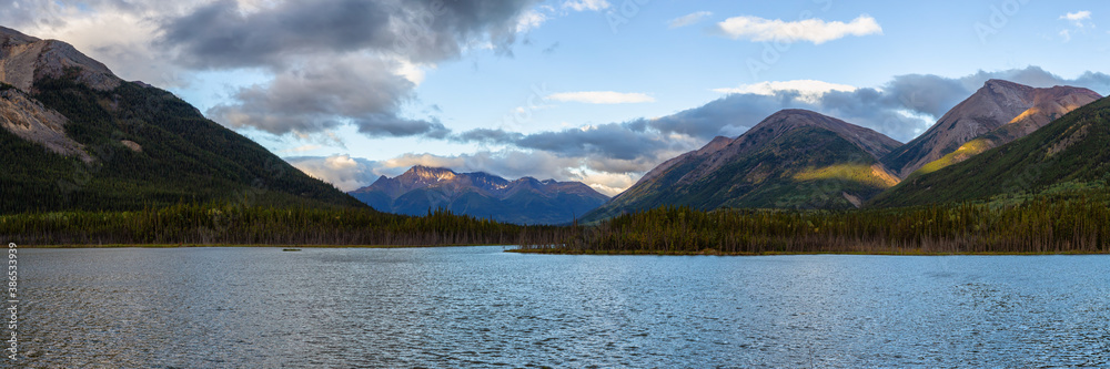 Panoramic View of Scenic Lake surrounded by Mountains and Trees on a Cloudy Morning at Sunrise in Canadian Nature. Taken in Northern British Columbia, Canada.