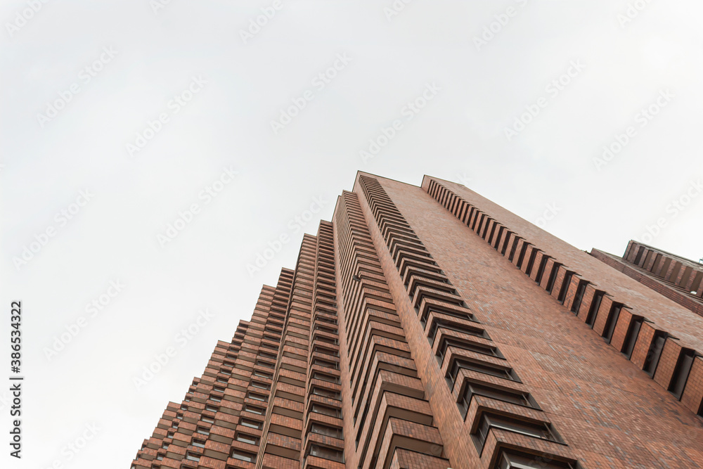 Low Angle view of a brick corner geometrical building with blue cloudy sky at sunny day