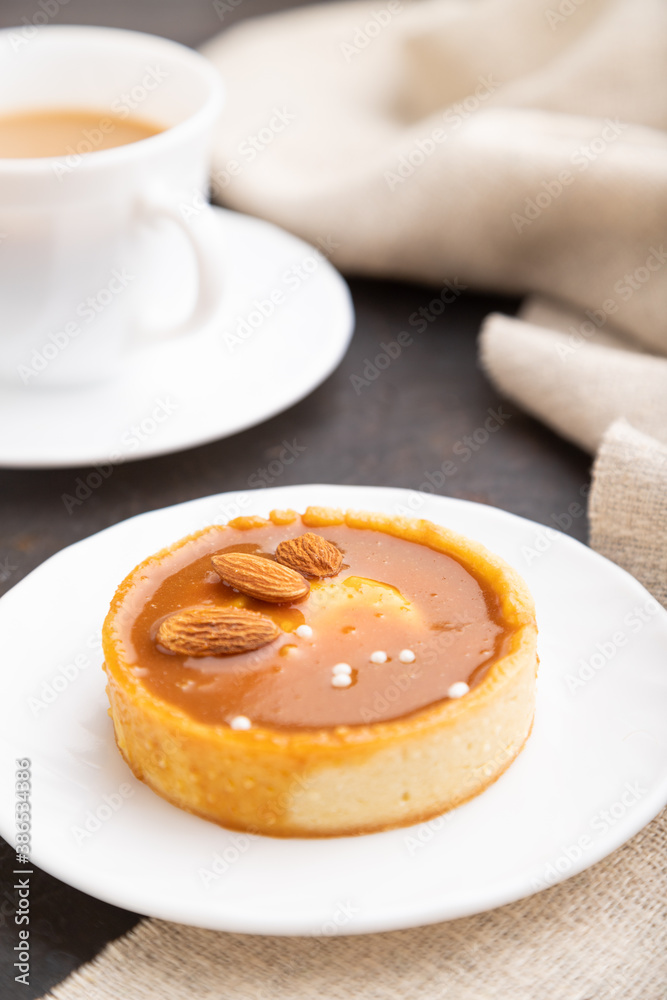 Sweet tartlets with almonds and caramel cream with cup of coffee on a black concrete background. Side view, selective focus. Sweet tartlets with almonds and caramel cream with cup of coffee on a black concrete background. Side view, selective focus.