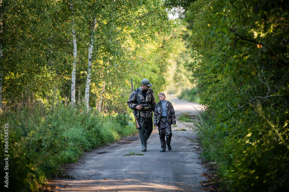 A young boy on the hunt with an experienced instructor in the forest. Autumn. Hunting for upland wildfowl.