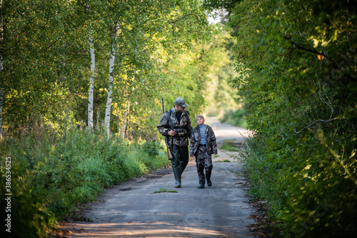 A young boy on the hunt with an experienced instructor in the forest. Autumn. Hunting for upland wildfowl.