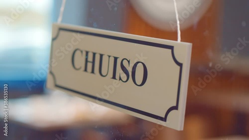 Close up of staff turning aperto chuiso sign hanging on glass door in italian restaurant. photo
